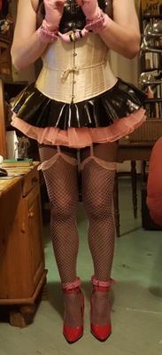 Sissy Maid erledigt Hausarbeiten in glänzendem Outfit.