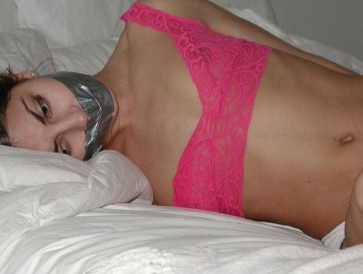 Junge Frau im Bett gefesselt und geknebelt